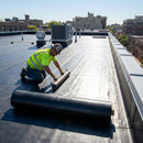 EPDM rubber sheet membrane being laid on flat roof by roofer - weatherproof roofing