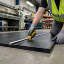 Industrial rubber sheet being cut to size in factory with Stanley knife and tape measure